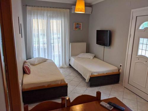 a bedroom with two beds and a table and a tv at Artemis Apartments in Lefkada