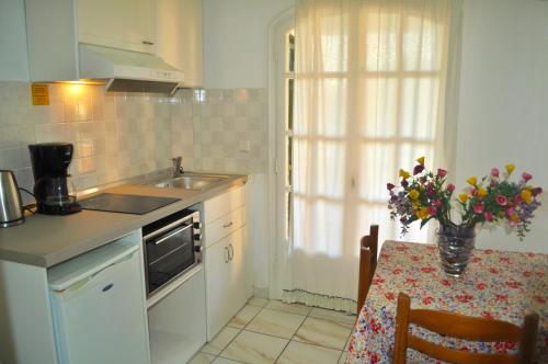 a kitchen with a sink and a table with a vase of flowers at Apartments Maria with Pool - Agios Gordios Beach in Agios Gordios