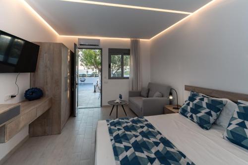 a bedroom with a bed and a couch and a television at POUNEDES LUXURY SUITES in Pefki Rhodes
