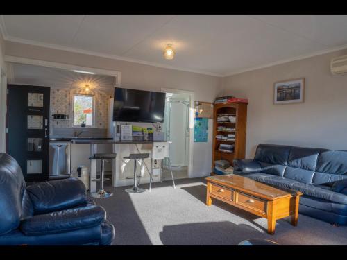 a living room with blue leather couches and a table at Te Anau Holiday Home - Free WIFi - Free Bikes & Kayaks - Short Walk to Lake & Town - Top Views in Te Anau