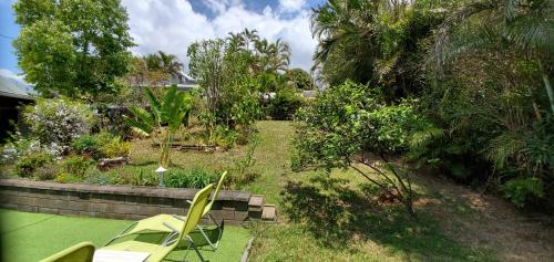 a garden with two chairs and a bench and trees at La Maison Dakoté in Sainte-Clotilde