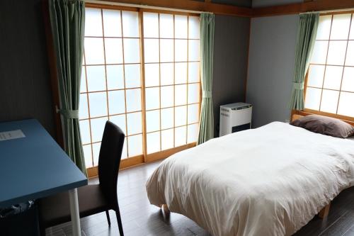 a bedroom with a bed and a desk and windows at 富貴の里レジデンス in Ombetsu