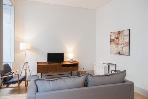 sala de estar con sofá y escritorio con TV en FLH Downtown Modern Art Flat, en Lisboa