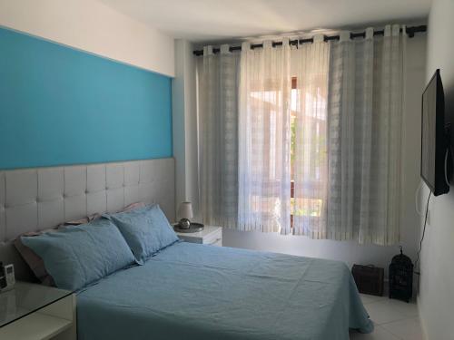 um quarto com uma cama azul e uma janela em Cond Enseada - Belissímo Vista Mar na Praia do Forte na Praia do Forte