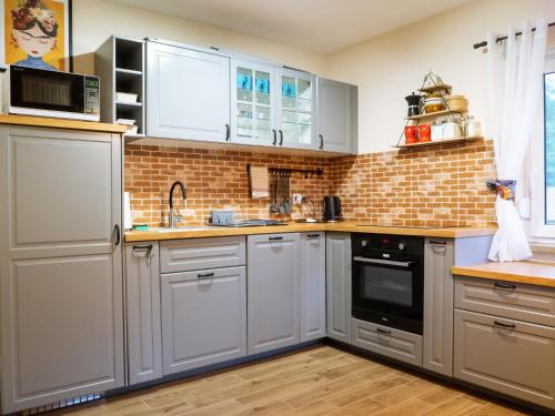 a kitchen with white cabinets and a brick wall at Załakowo Na Gwizdówce 13 całoroczny domek na Kaszubach in Załakowo