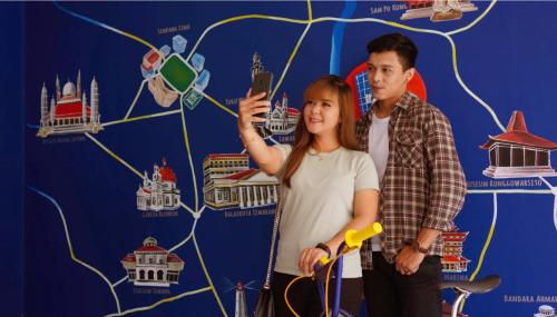 a man and a woman standing in front of a wall at Hotel Youstay Semarang by Sinergi in Kalibanteng-lor