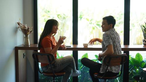 a man and a woman sitting at a table at Hotel Youstay Semarang by Sinergi in Kalibanteng-lor