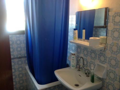 a bathroom with a blue shower curtain and a sink at IRAKLIOS- Fabulous area- ,,,- sea-view- Studios with parking,-46m2-just call for price, vacancy etc- next to Vallis hotel -20meters from seaside!!! in Agria