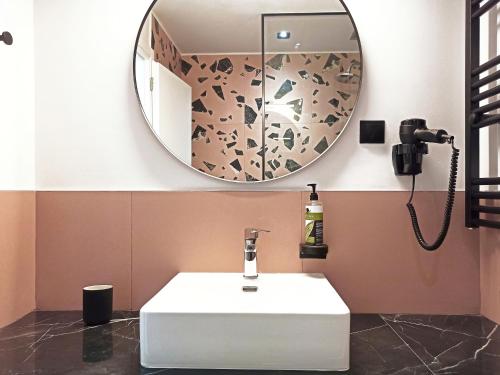 ein Badezimmer mit einem weißen Waschbecken und einem Spiegel in der Unterkunft Dioni Hotel in Ioannina