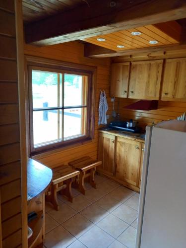 eine Küche mit Holzschränken, einem Fenster und einem Kühlschrank in der Unterkunft Brīvdienu māja Greiži in Dzirciems