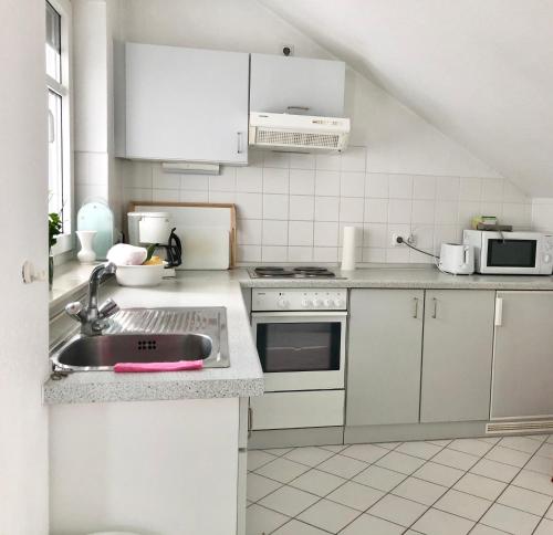 cocina blanca con fregadero y microondas en Ferienwohnung Villy Seepark 711, en Heringsdorf