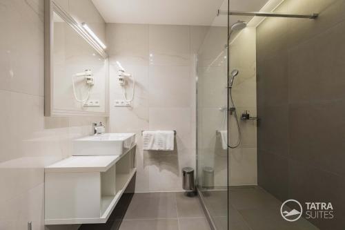 uma casa de banho branca com um lavatório e um chuveiro em TATRA SUITES Boutique Suites Deforte Gallery 202 em Poprad