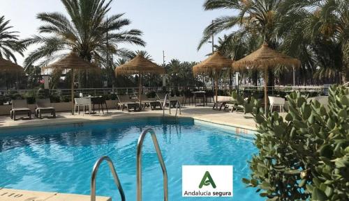 una piscina con sillas y sombrillas en Ohtels Gran Hotel Almeria, en Almería