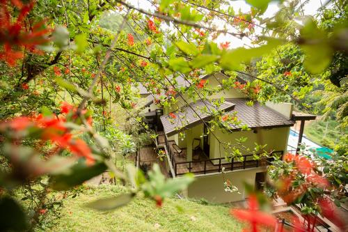 a small building with red flowers in the trees at Huluganga Ridge, Kandy in Kandy