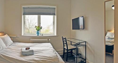 a bedroom with a bed and a desk and a window at Villa Sofie Bed & Breakfast in Haslev