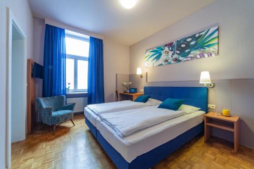 a hotel room with a large bed and a chair at Stadthotel in Kaiserslautern