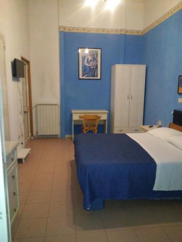 維亞雷焦的住宿－摩根娜別墅酒店，一间卧室配有一张床、一张桌子和一面蓝色的墙壁