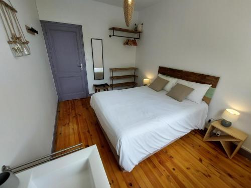 1 dormitorio con cama blanca y puerta azul en Gite des vendangeurs 4 étoiles - 10 personnes, en Bourg-sur-Gironde