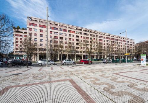 a large building with cars parked in a parking lot at Gestión de Alojamientos Apartments in Pamplona