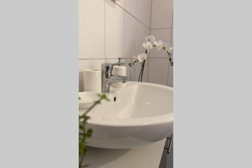 lavabo blanco en el baño con azulejos blancos en HAVEN STUUV - Zentral mit Balkon, en Bremerhaven