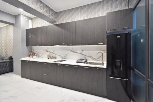 a kitchen with brown cabinets and a black refrigerator at Teryan street,1 bedroom Modern, New Eurorenovated apartment TT881 in Yerevan