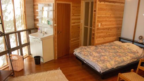 ein Schlafzimmer mit einem Bett in einem Holzzimmer in der Unterkunft Glamping Himeshara - Vacation STAY 43046v in Kirishima