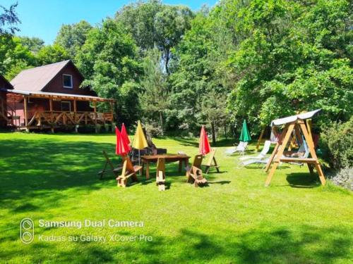 a picnic table with chairs and umbrellas in a yard at Taparynė in Alanta