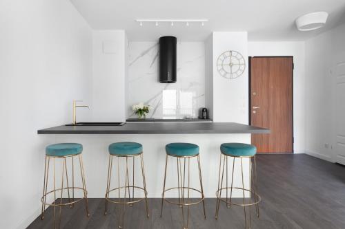a kitchen with three bar stools and a counter at Elite Apartments Nadmotławie Prestige in Gdańsk