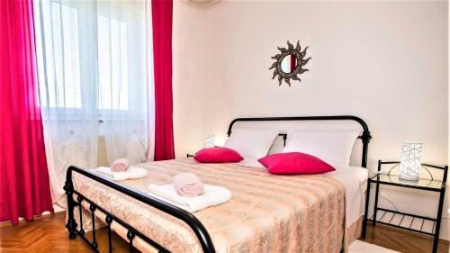ein Schlafzimmer mit einem Bett mit zwei rosa Kissen darauf in der Unterkunft Apartment Green Oasis 1 in Umag