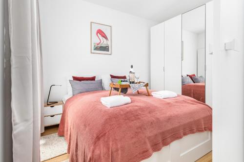 a white bedroom with a large bed with a red blanket at Apartamenty Południowa 14 by Renters in Dźwirzyno