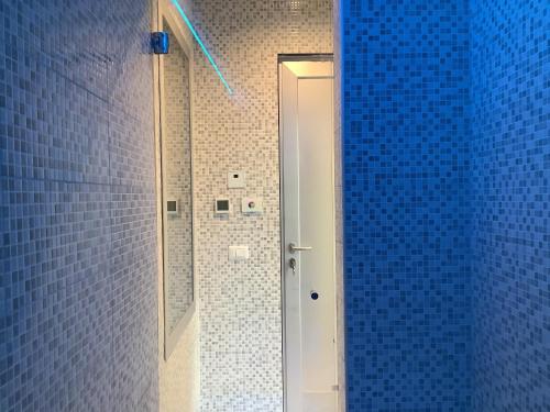 a blue tiled bathroom with a shower with a glass door at Colonno Panoramica Lago Di Como in Colonno