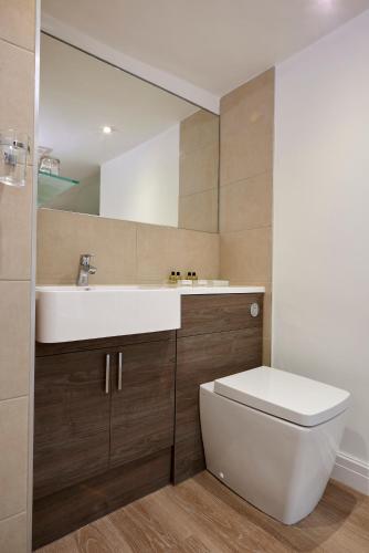 a bathroom with a sink and a toilet and a mirror at Last Drop Village Hotel & Spa in Bolton