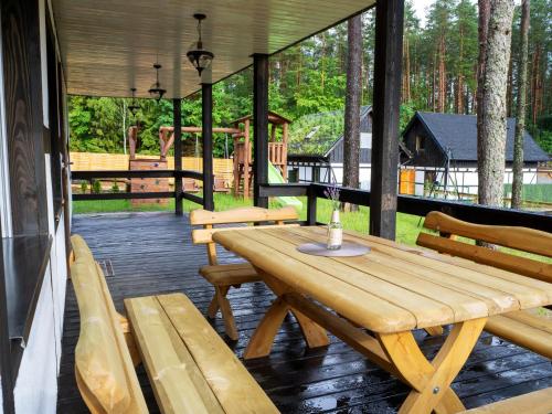 une table en bois et des bancs sur la terrasse couverte d'une cabine dans l'établissement Załakowo Na Gwizdówce 13 całoroczny domek na Kaszubach, à Załakowo