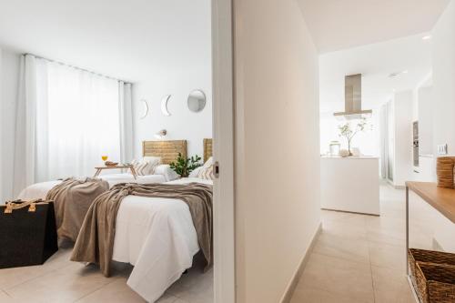 a white bedroom with two beds and a kitchen at Apartamentos Martalia Nerja in Torrox