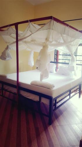 a white bed with a canopy in a room at Farmhouse Lodge in Dar es Salaam