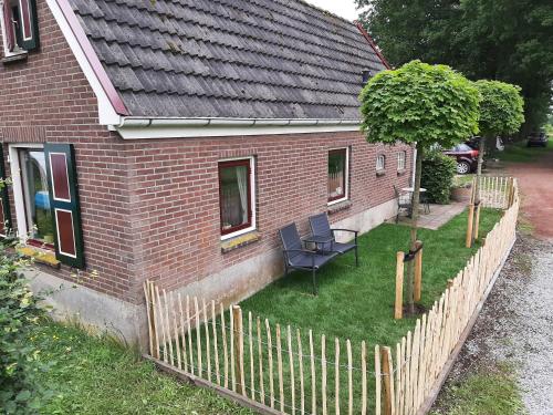 ein Haus mit einem Zaun, einem Tisch und einem Baum in der Unterkunft Bakhuisje in Emst