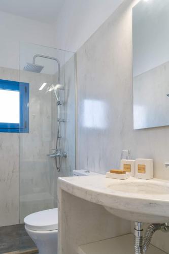 a white bathroom with a sink and a toilet at Blue Moon Apartments in Makry Gialos