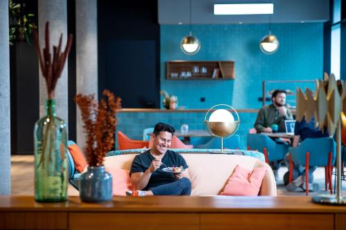 a man sitting on a couch in a living room at KONCEPT HOTEL International in Cologne