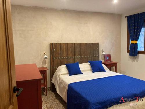 a bedroom with a large bed with blue pillows at Casa Rural Abuelo Teo in Campo de Criptana