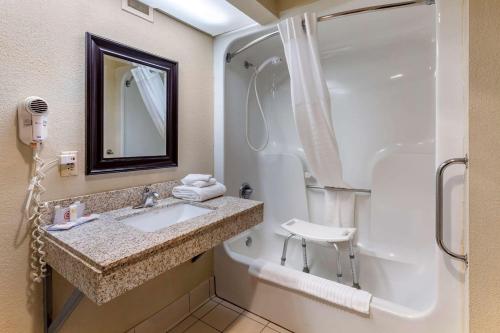 a bathroom with a sink and a tub and a mirror at Comfort Inn Alliance in Alliance