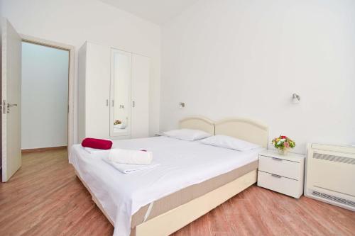 a white bedroom with a large bed and a tv at Victoria Center Apartments in Budva