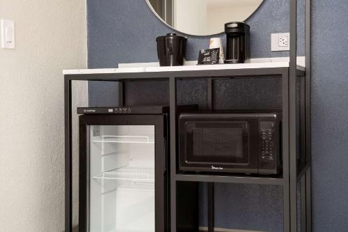 a microwave on a shelf next to a refrigerator at Rodeway Inn St Augustine Historic District in Saint Augustine