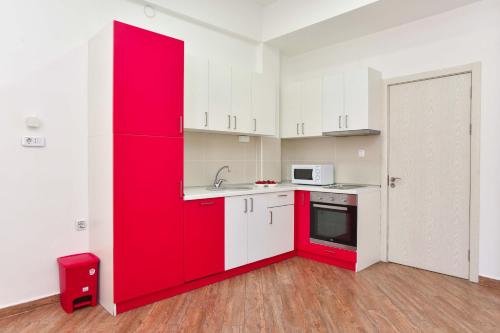 a red kitchen with white cabinets and a red refrigerator at Victoria Center Apartments in Budva