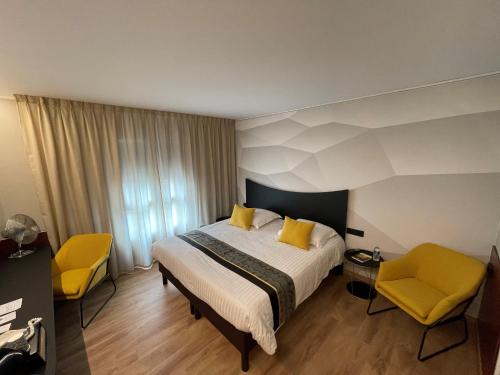 une chambre d'hôtel avec un lit et deux chaises jaunes dans l'établissement Logis Hotel Center, à Brest