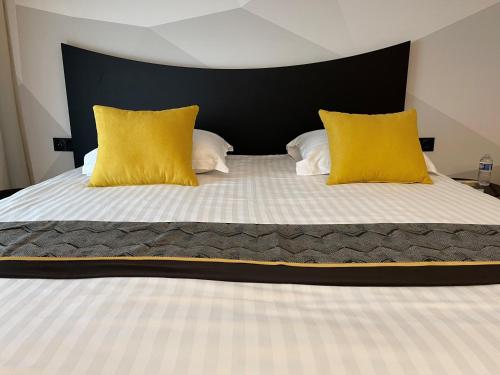 a bed with a white comforter and two pillows at Logis Hotel Center in Brest