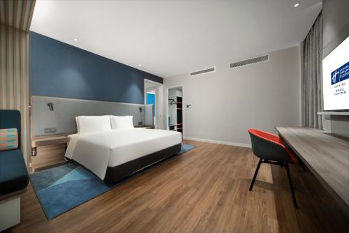 a bedroom with a bed and a desk and a tv at Holiday Inn Express Zhuhai Gongbei by IHG in Zhuhai