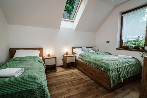 2 Betten in einem Zimmer mit grüner Bettwäsche und einem Fenster in der Unterkunft Domki nad Stawami in Ujanowice