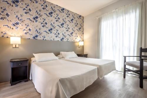 1 dormitorio con cama y papel pintado azul y blanco en Apartamentos HG Cristian Sur, en Los Cristianos