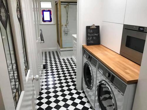 a laundry room with a black and white checkered floor at Waterside Cottage in Daylesford