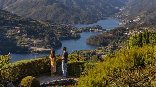 a man and a woman standing on a mountain overlooking a river at Pousada Geres-Caniçada in Geres